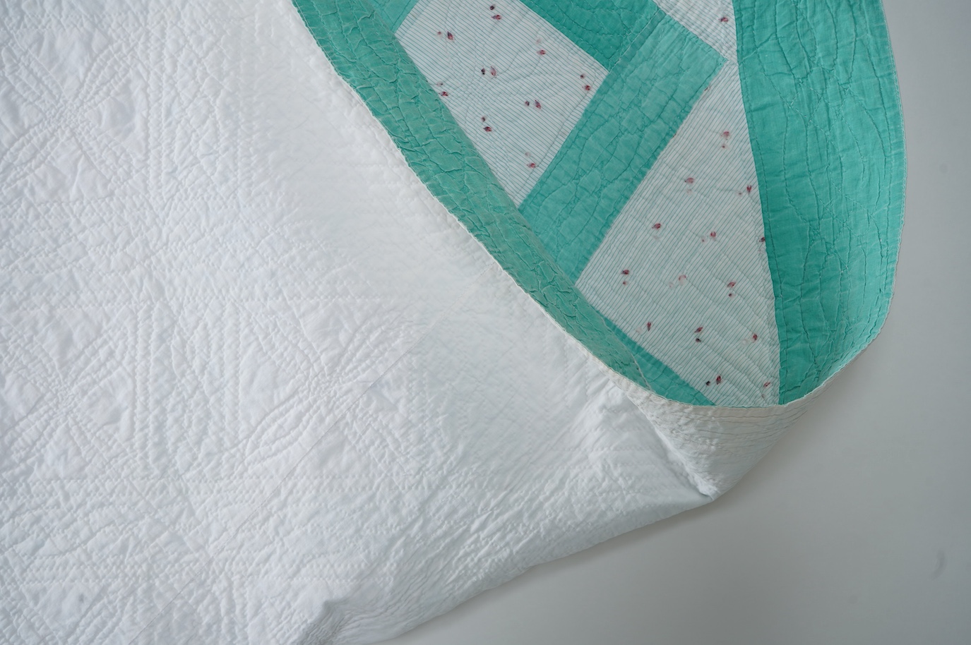 A late 19th early 20th century English, Durham, immaculately hand quilted bedcover. Designed using a plain mint green cotton and a complimentary light floral cotton stripe, in an all over lattice design, with a mint gree